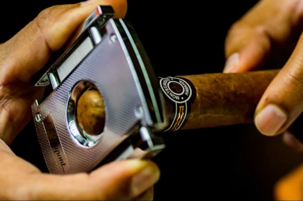 A cigar being cut with a cigar cutter